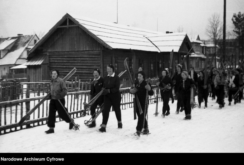 Turystki niosące narty.