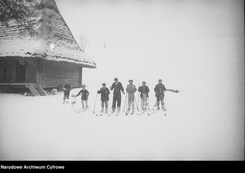 Narciarze przy budynku.