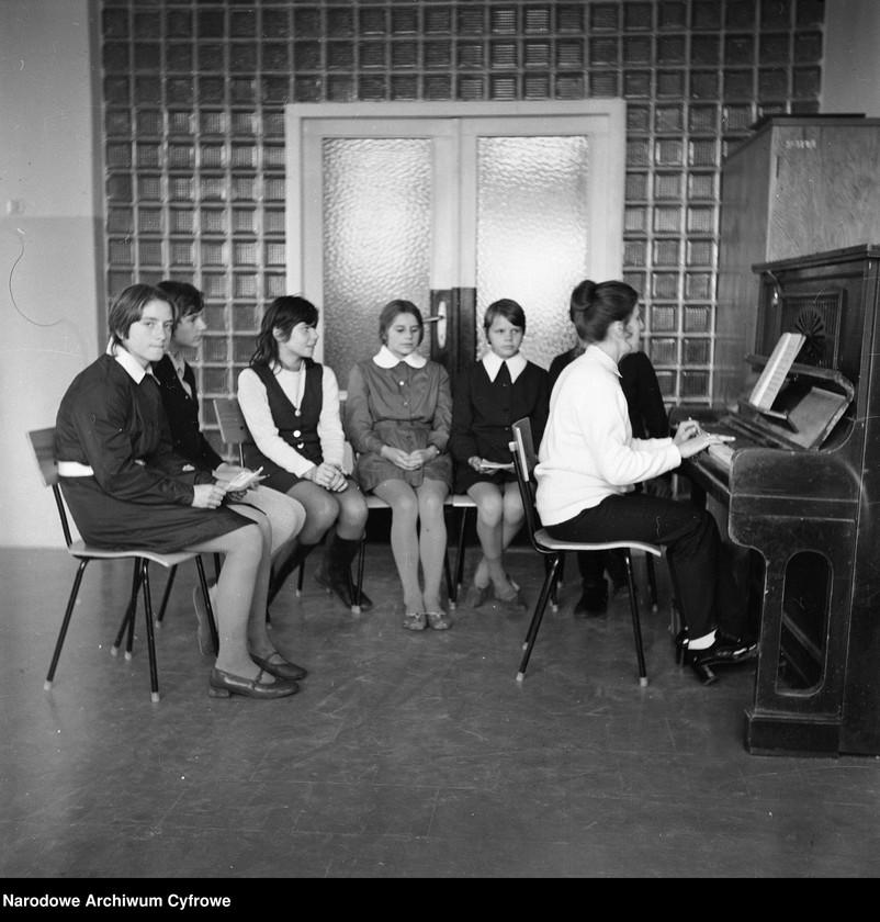 Lekcja muzyki. Nauczycielka Janina Bochmulska gra na pianinie.