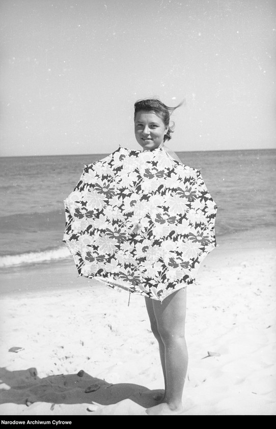 Kobieta z parasolem na plaży.
