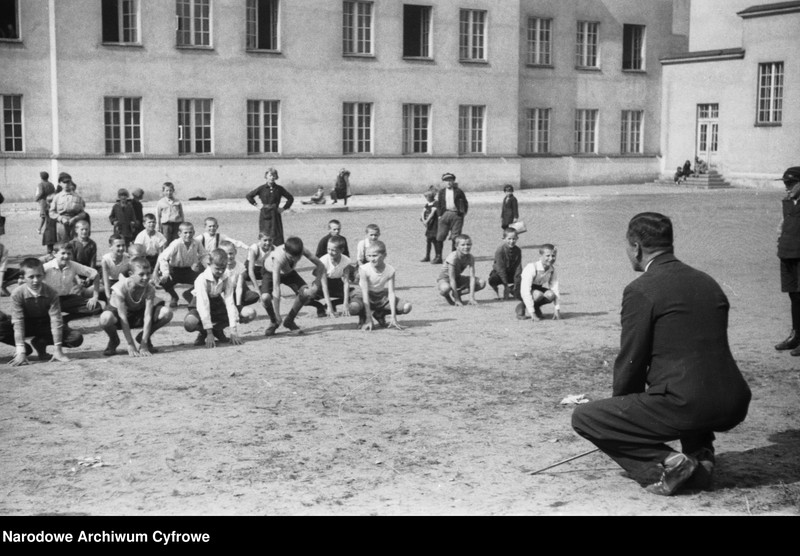 Lekcja gimnastyki przed budynkiem szkoły.