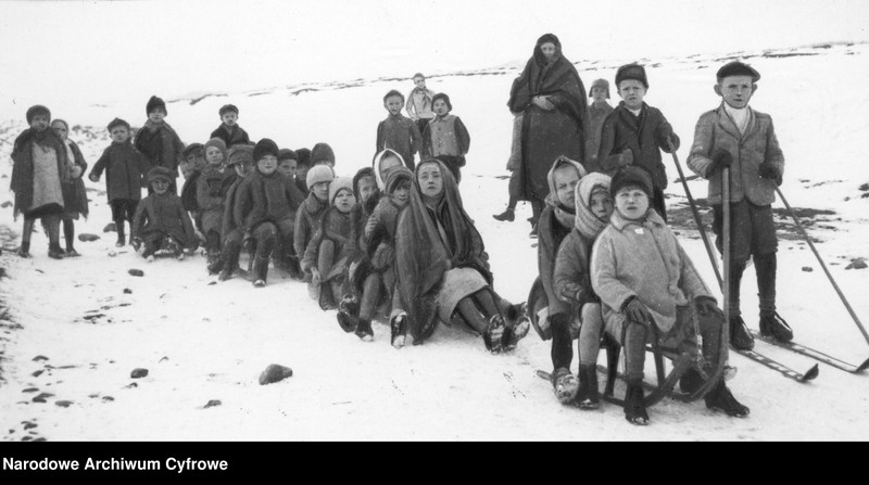 Uczniowie zjeżdżają na sankach i nartach podczas lekcji gimnastyki.